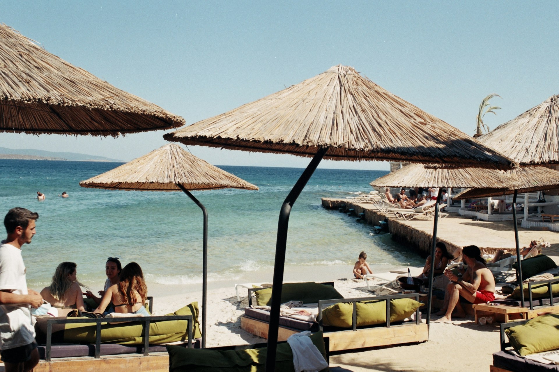 a group of people sitting on top of a sandy beach